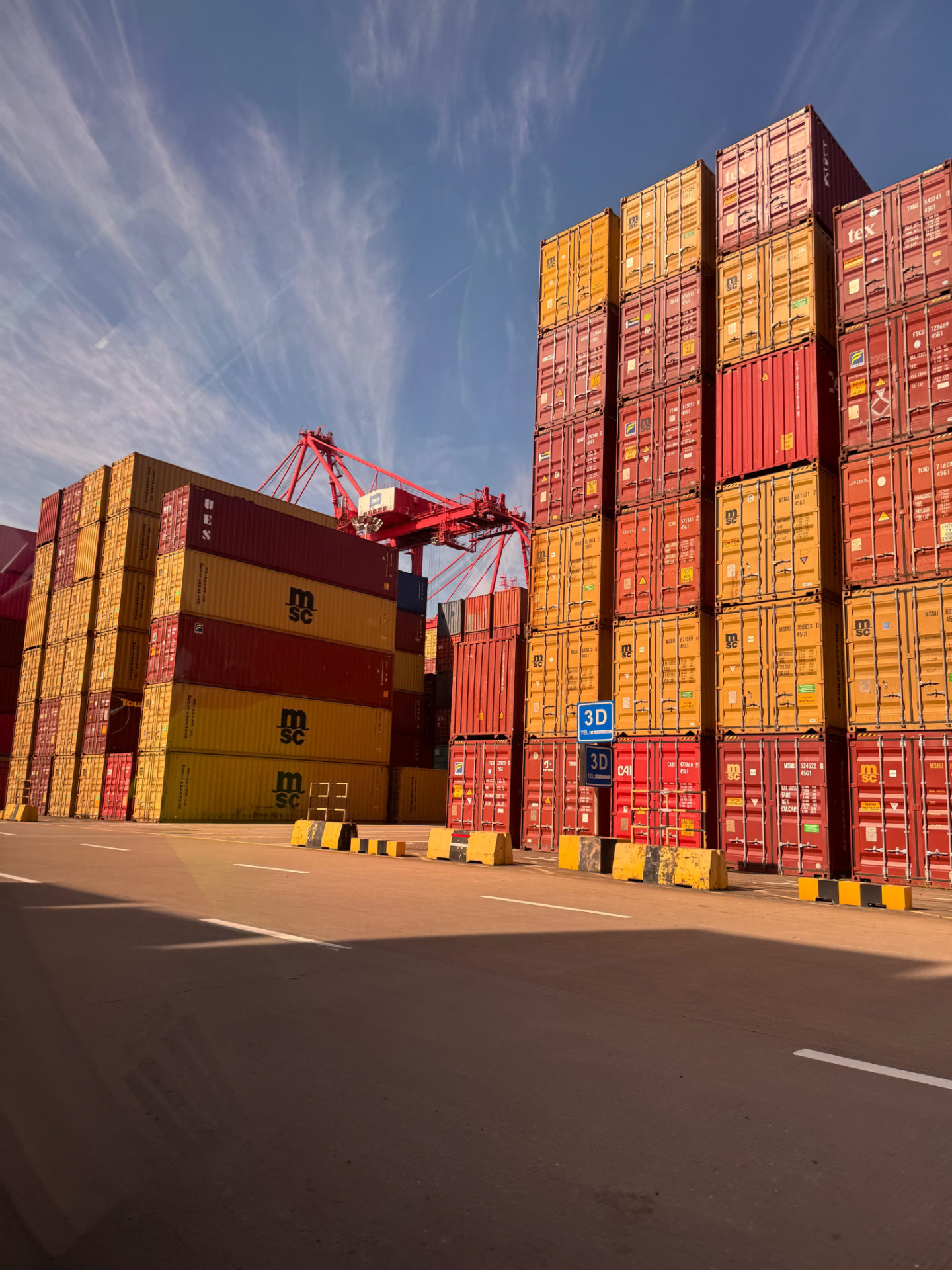 Tall rows of red and yellow containers beside a crane